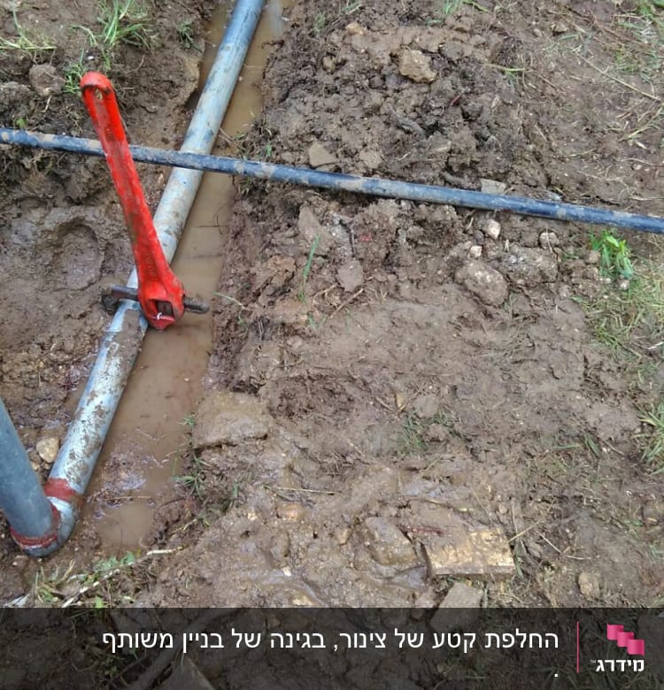 צינורות מים באדמה עם מפתח צינורות אדום